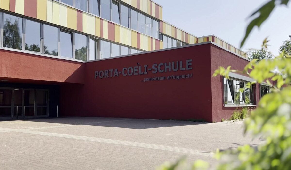 Eingang zur Porta-Coeli-Schule mit modernem Design und farbenfroher Fassade, umgeben von einem gepflegten Schulgelände.