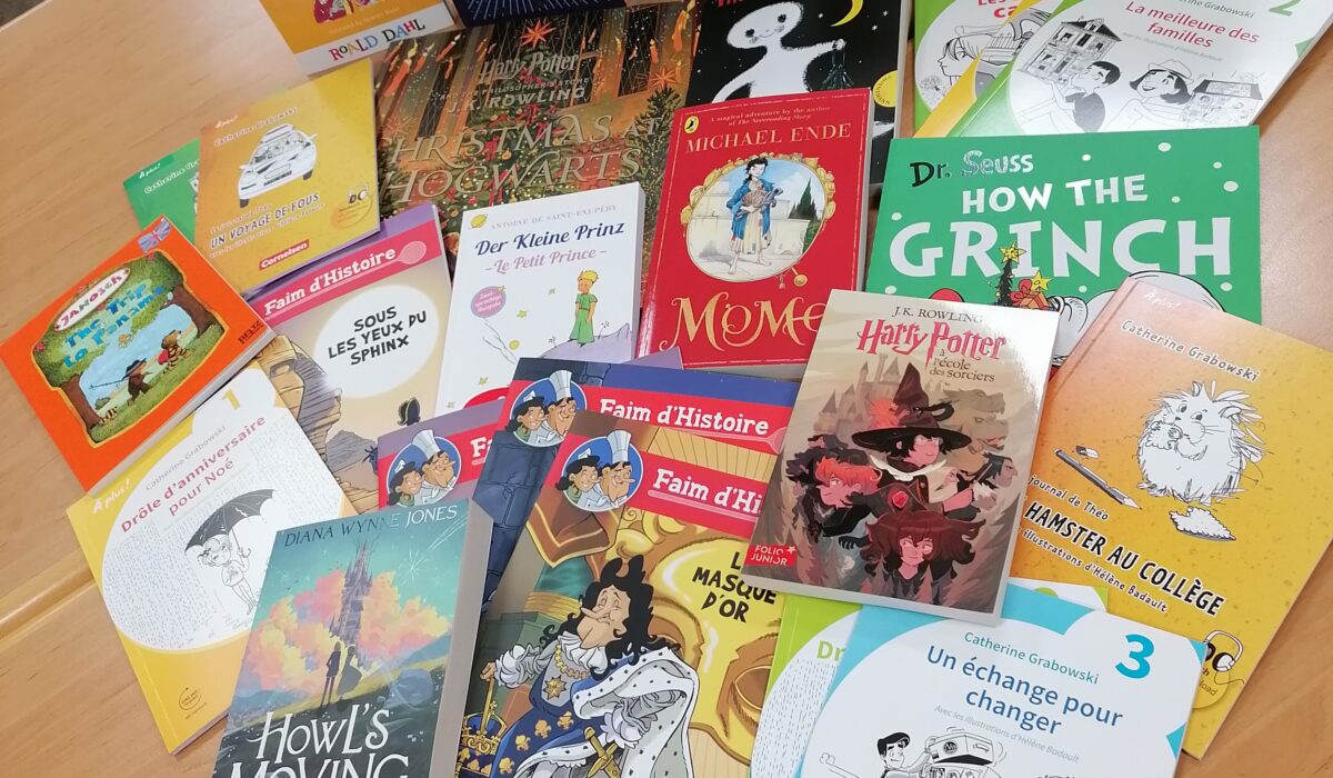 Bunte Auswahl an Kinder- und Jugendbüchern auf einem Tisch, darunter Titel wie "Charlie und die Schokoladenfabrik", "Die kleine Hexe", "Sherlock Holmes", "Der kleine Prinz" und "Howl's Moving Castle". Ideal für Leseratten und Buchliebhaber.